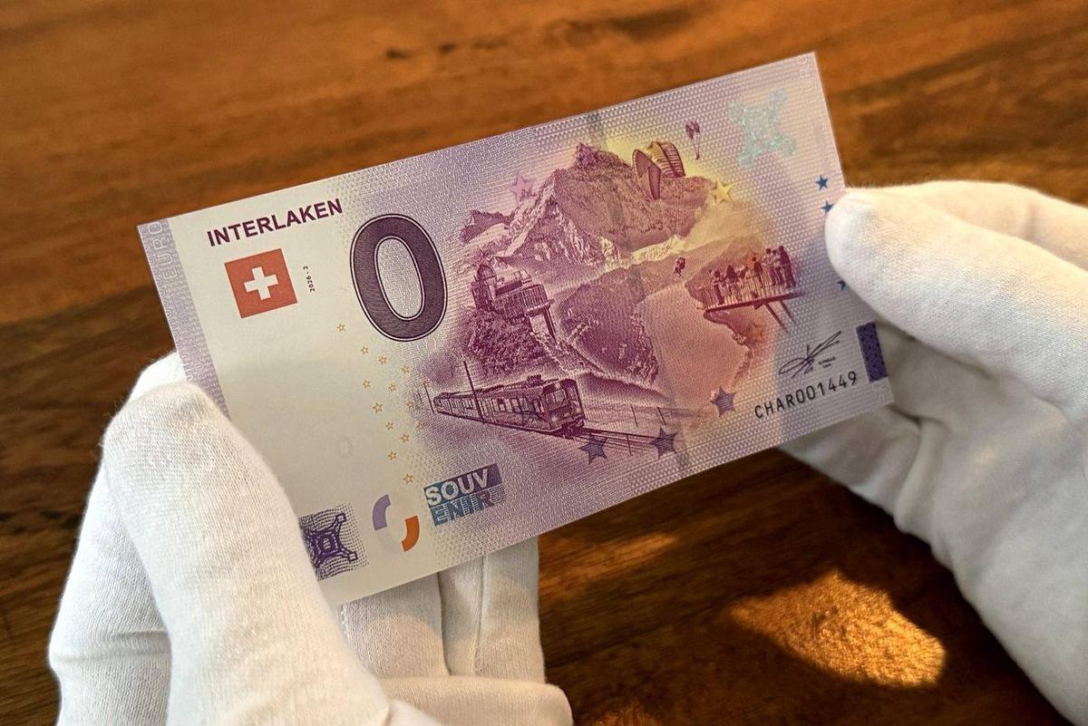 A 0 euro note from Interlaken held in white gloves