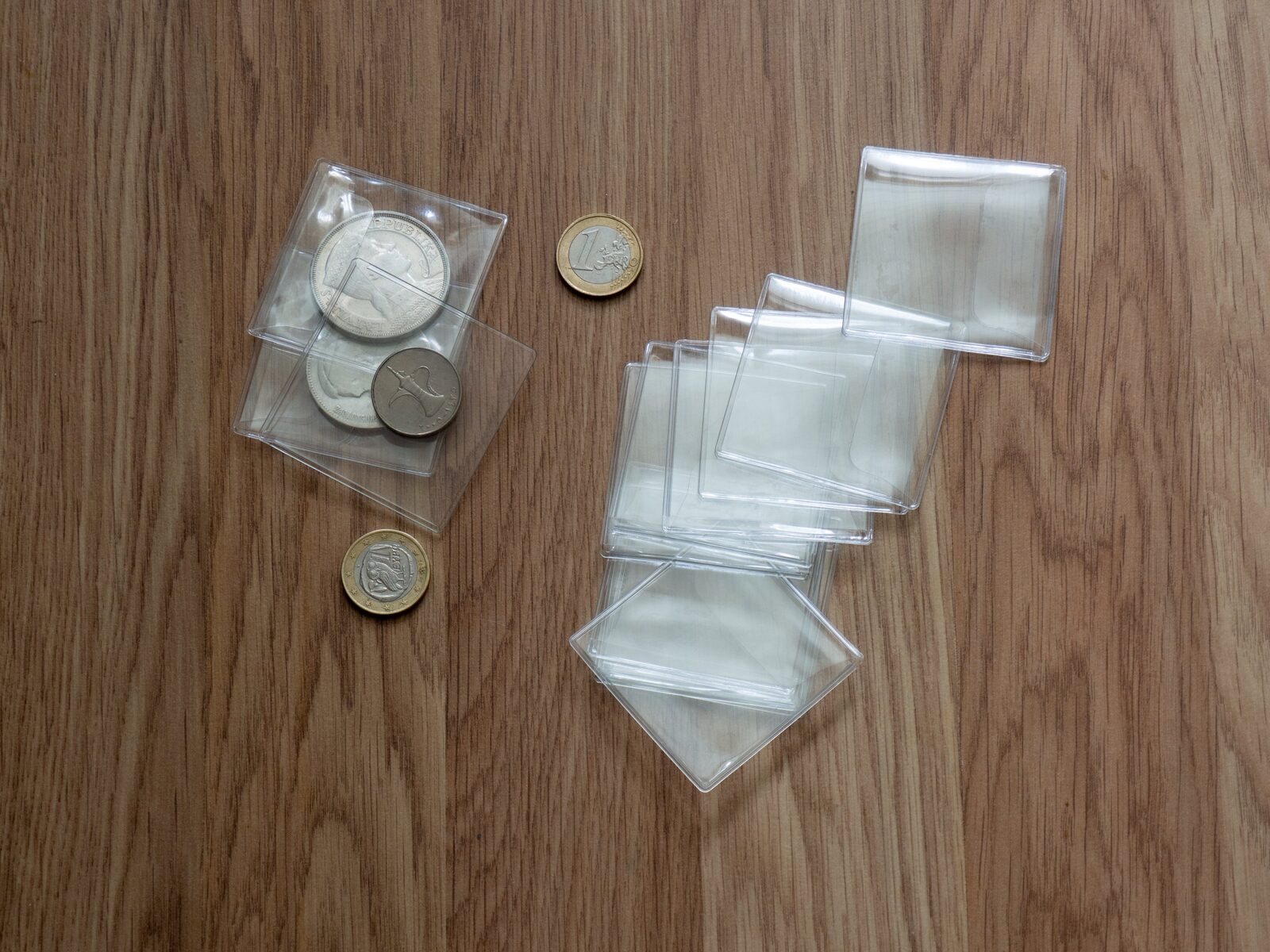 Coins in clear plastic sleeves on a wooden table