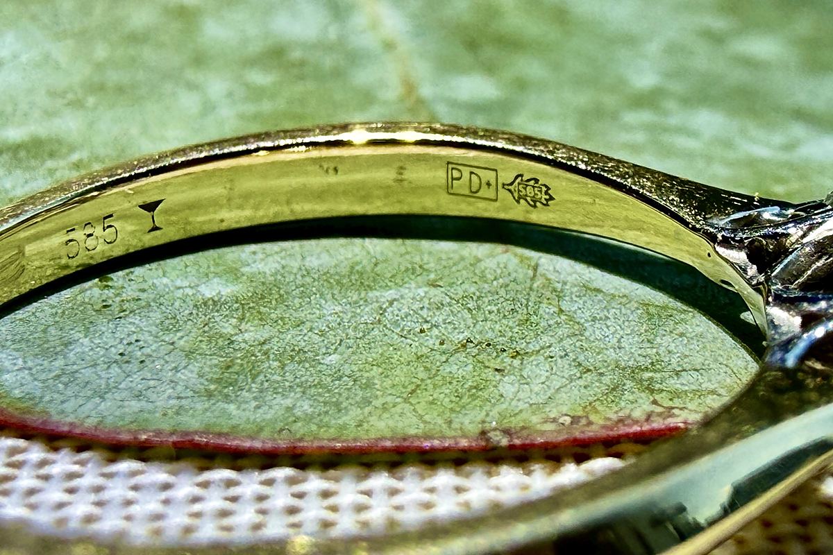 Nahaufnahme der Punzen in einem Goldring: 585, ein kleines Cocktailglas, PD+ in einem Rechteck und ein Eichenblatt mit 585