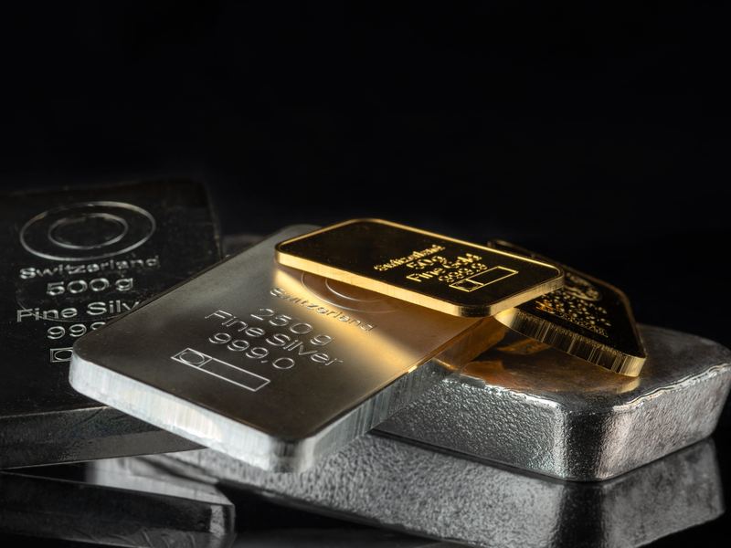 Silver bars and small gold bars on a black surface